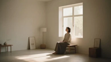 Sade bir odada ışık dolu pencere önünde oturan bir kişi, etrafında sade eşyalar, huzurlu bir atmosfer. Minimalizm felsefesini yansıtan bir sahne.